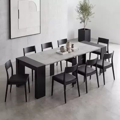 Mesa de jantar cinza com cadeiras pretas e vasos decorativos num ambiente minimalista