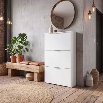 Móvel branco com três portas e espelho redondo numa sala com banco de madeira, plantas em vasos e candeeiros pendentes.