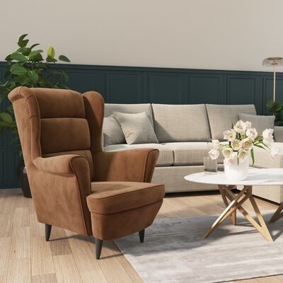 Cadeirão castanho acolchoado numa sala com sofá cinzento e mesa de centro branca com flores