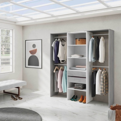 Roupeiro modular aberto cinza e branco com roupas penduradas e prateleiras numa sala luminosa.