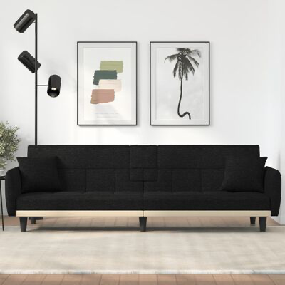 Sofá preto de quatro lugares numa sala minimalista com candeeiro de chão e duas imagens emolduradas na parede