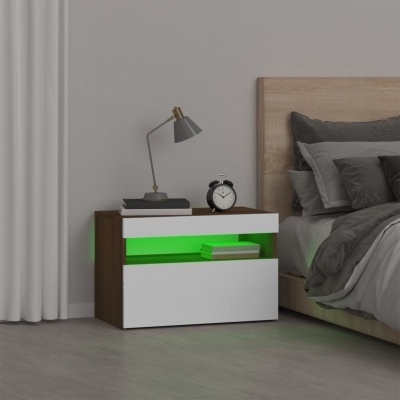 Mesa de cabeceira branca e castanha com iluminação verde e candeeiro, ao lado de cama com roupa cinzenta