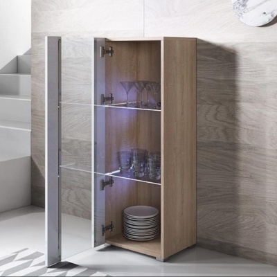 Móvel de madeira clara com porta em vidro transparente contendo copos, taças e pratos.