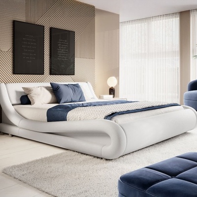 Cama de casal estofada branca com roupa de cama azul e branca numa sala com tapete branco e quadros pretos na parede.