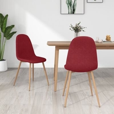 Duas cadeiras vermelhas estofadas com pernas de madeira clara em sala com mesa e decoração
