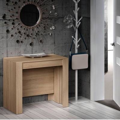 Mesa dobrável de madeira clara numa entrada com parede cinzenta, espelho decorativo, cabide com chapéu e mala e porta branca aberta