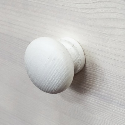 Puxador redondo branco de madeira num painel branco