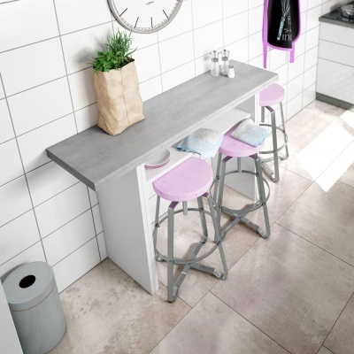 Mesa alta cinzenta com três bancos altos cor-de-rosa e azuis junto a parede de azulejos brancos.