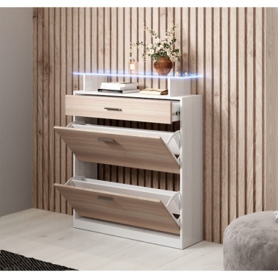 Móvel branco e madeira clara com três compartimentos, vaso de flores, livros, parede de madeira