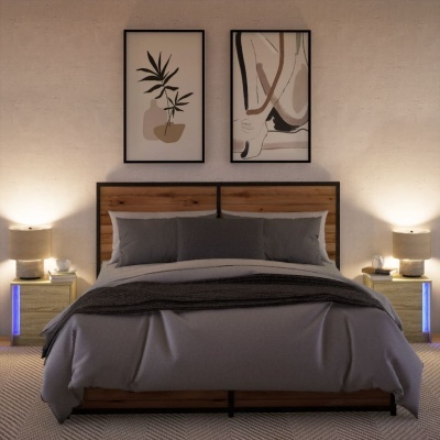 Quarto com cama de madeira e ferro, roupa de cama cinza, duas mesas de cabeceira com candeeiros e quadros abstratos na parede.