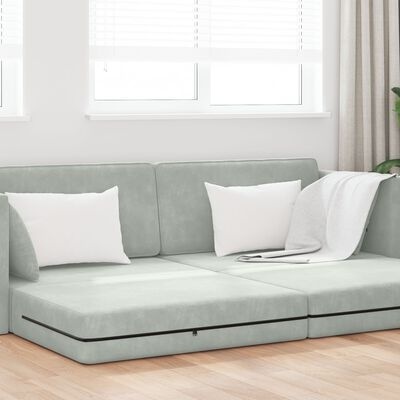 Sofá chaise longue cinza claro com almofadas brancas e manta numa sala moderna