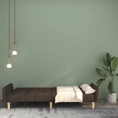 Sofá-cama castanho escuro com cobertor branco numa sala verde com candeeiros pendurados e planta