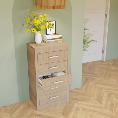 Móvel de madeira clara com cinco gavetas, vaso com flores amarelas, livros e quadro decorativo num ambiente interior.