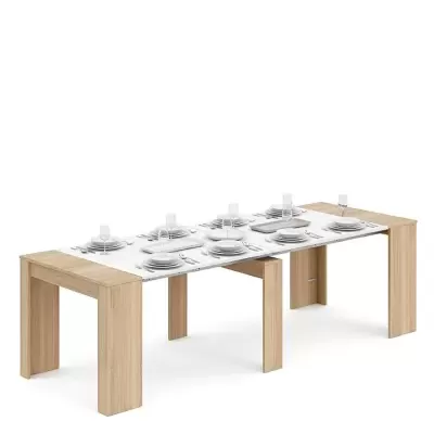 Mesa de jantar extensível branca com pernas de madeira clara, posta para 6 pessoas, em fundo branco.