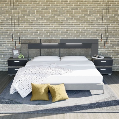 Quarto com cama de casal preta e cinza, roupa branca, manta branca texturada, almofadas amarelas, mesas de cabeceira pretas e parede de tijolos cinza.