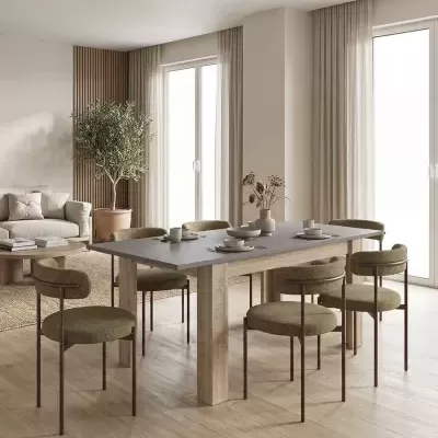 Mesa de jantar com tampo cinzento e cadeiras verdes num ambiente minimalista com cortinas bege e planta em vaso de barro
