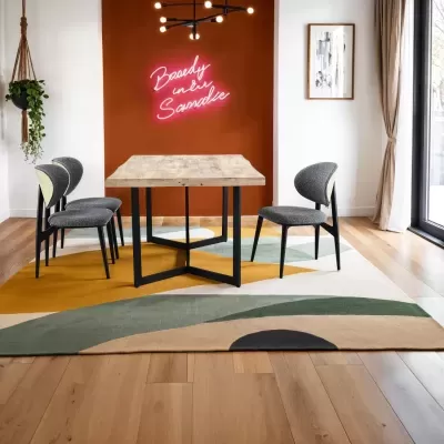 Mesa de jantar em madeira com quatro cadeiras estofadas cinza e letreiro neon numa parede laranja