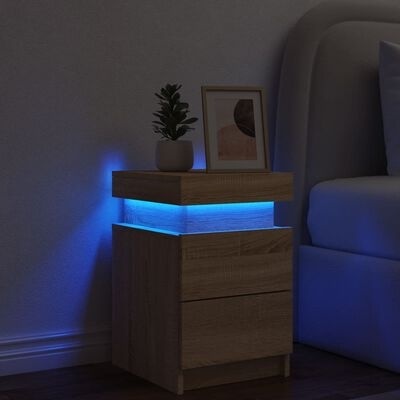 Mesa de cabeceira de madeira clara com luz azul e decoração ao lado de cama cinza