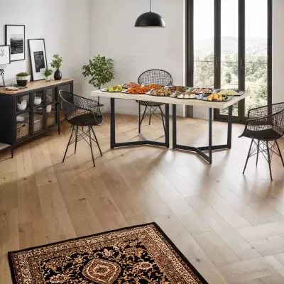 Sala de jantar moderna com mesa de madeira clara, cadeiras de metal pretas e buffet preto com decoração e pratos sobre a mesa.