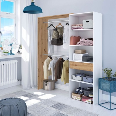 Armário branco e madeira com roupas penduradas e prateleiras organizadas num quarto luminso