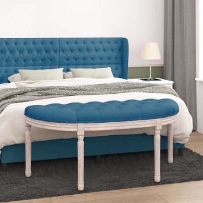 Cama azul com cabeceira capitonê, banco oval estofado azul e mesa de cabeceira com candeeiro