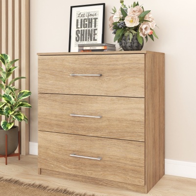 Cômoda de madeira clara com três gavetas e decoração no topo