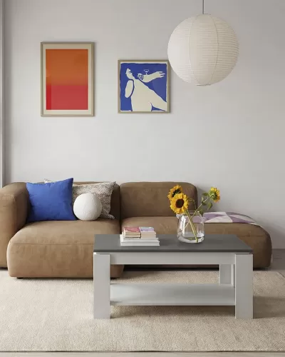 Sala de estar com sofá castanho, almofadas coloridas, mesa baixa com vaso de girassóis, quadros abstratos e candeeiro pendente branco.