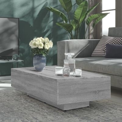 Mesa de centro em madeira clara com vaso de flores e conjunto de vidro numa sala moderna.