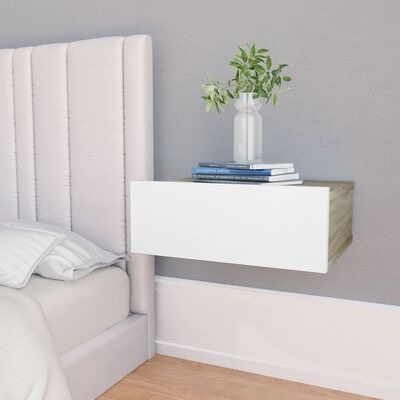 Mesa de cabeceira flutuante branca com livros e vaso com plantas ao lado de cama com cabeceira cinza