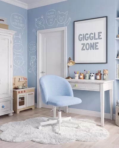Cadeira azul clara em quarto infantil com parede azul decorada e mesa branca.