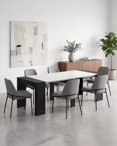 Conjunto de sala de jantar com mesa extensível branca e pés pretos, seis cadeiras cinzentas e aparador de madeira com planta