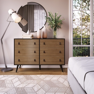 Cômoda de madeira com seis gavetas, candeeiro de pé e espelho redondo numa decoração de quarto