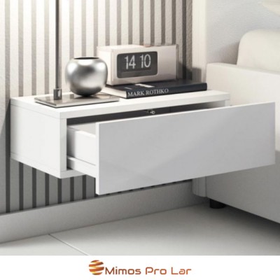 Mesa de cabeceira branca suspensa com gaveta aberta e decoração, ao lado de sofá branco