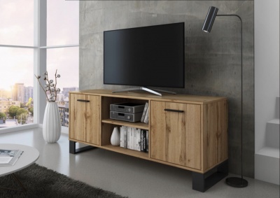 Móvel de televisão em madeira clara com portas e compartimentos abertos, candeeiro de pé preto e parede cinza.