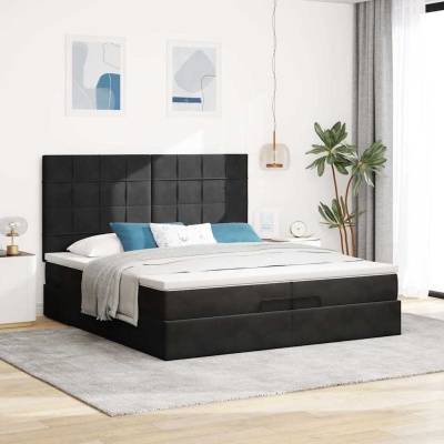 Cama de casal preta estofada com roupa de cama branca e cinza numa sala iluminada