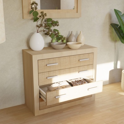 Cómoda de madeira clara com três gavetas e vasos cerâmicos no topo numa sala iluminada