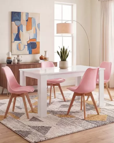 Conjunto de mesa branca com quatro cadeiras cor-de-rosa numa sala de jantar iluminada e decorada com móvel, quadro, planta e candeeiro