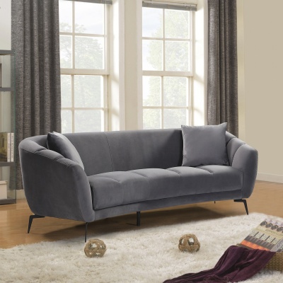 Sofá cinzento escuro de três lugares numa sala com tapete branco e janelas grandes