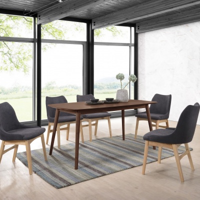 Mesa de jantar de madeira escura com quatro cadeiras cinzentas e tapete listrado numa sala iluminada