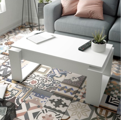 Mesa de centro branca sobre pavimento de azulejos coloridos, com sofá cinza e almofadas cor de rosa ao fundo