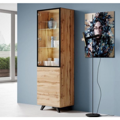 Móvel alto em madeira clara com porta de vidro e prateleiras, ao lado de quadro e candeeiro