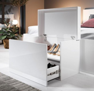Cubo de arrumação branco lacado aberto com sapatos dentro ao lado de uma cama