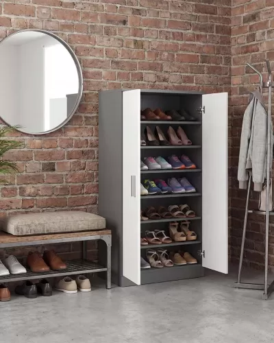 Armário de sapatos cinzento e branco aberto junto a banco com sapatos e parede de tijolo