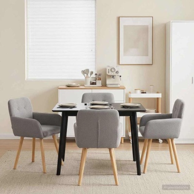 Mesa de jantar preta com quatro cadeiras cinza e móveis brancos ao fundo