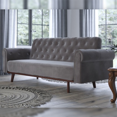 Sofá cinzento de três lugares com estofado capitonê e pés de madeira numa sala com janelas e cortinas