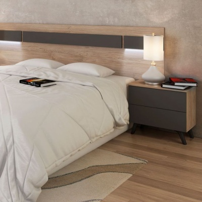 Quarto com cama de madeira clara, roupa de cama branca, mesa de cabeceira cinza com candeeiro e livros