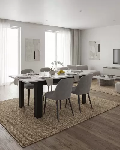 Mesa de jantar com quatro cadeiras cinzentas sobre tapete bege em sala com chão de madeira e paredes brancas.