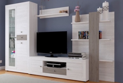 Móvel de sala de estar em madeira clara com detalhes cinza, suporte TV preto e decoração com livros, flores e velas