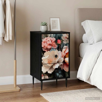 Mesa de cabeceira preta com gavetas florais ao lado da cama e cabide de roupa.