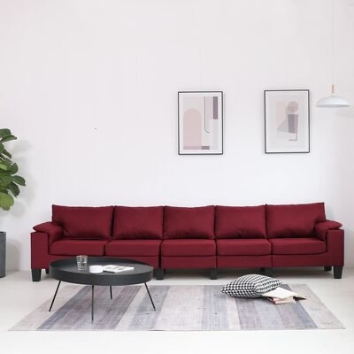 Sofá vermelho escuro de seis lugares num ambiente moderno com mesa de centro preta e decoração minimalista.
